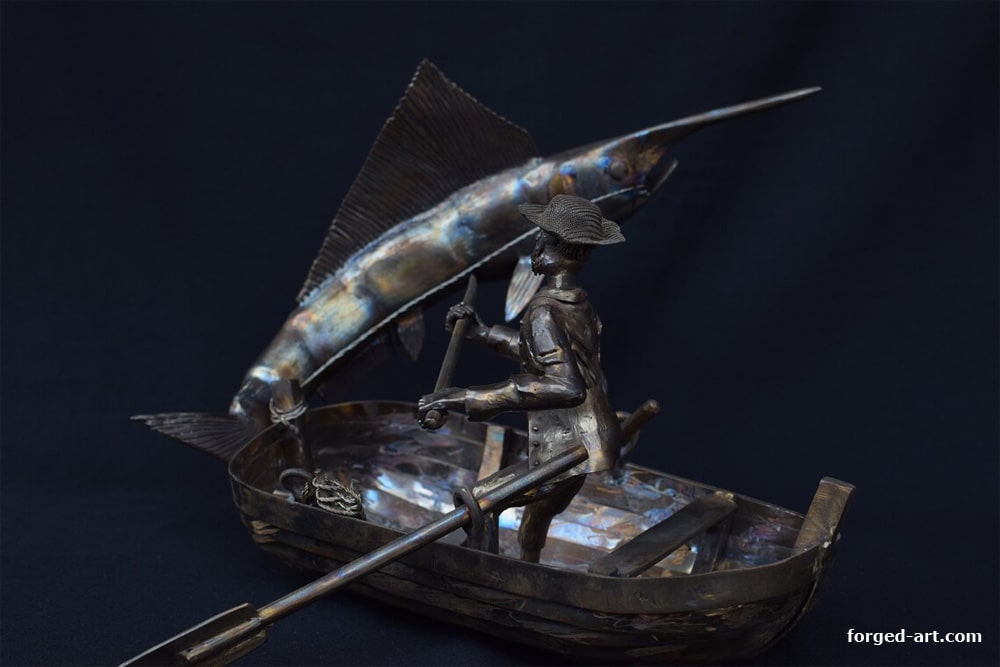 Steel sculpture of a fisherman catching a fish on a boat
